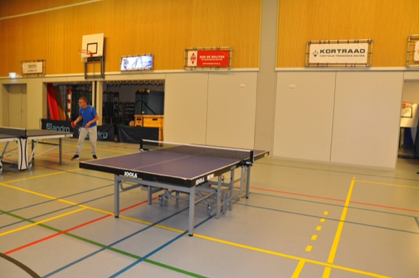 Leden spelen tafeltennis in de zaal